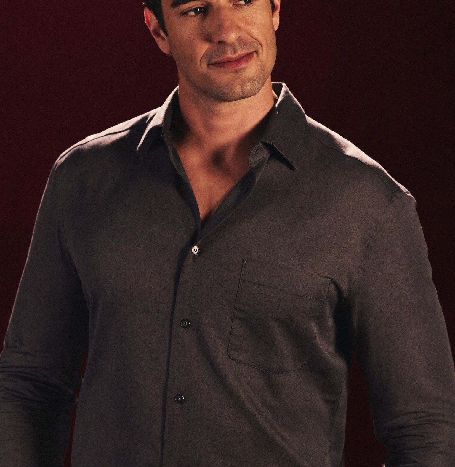 A calm, confident man in a fitted shirt, at ease